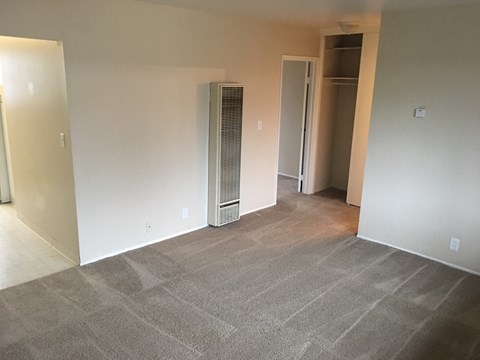 an empty living room with a heater in the corner