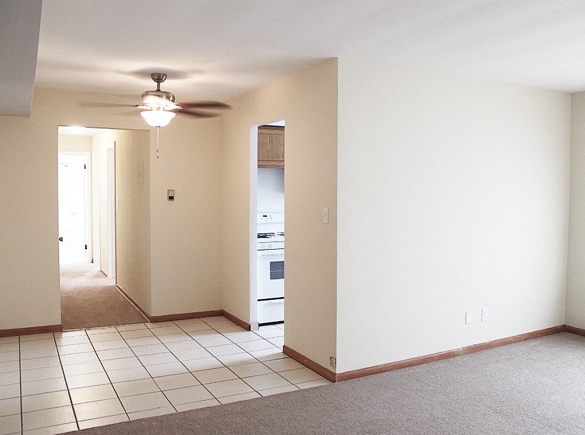 an empty living room with a ceiling fan and a tiled floor
