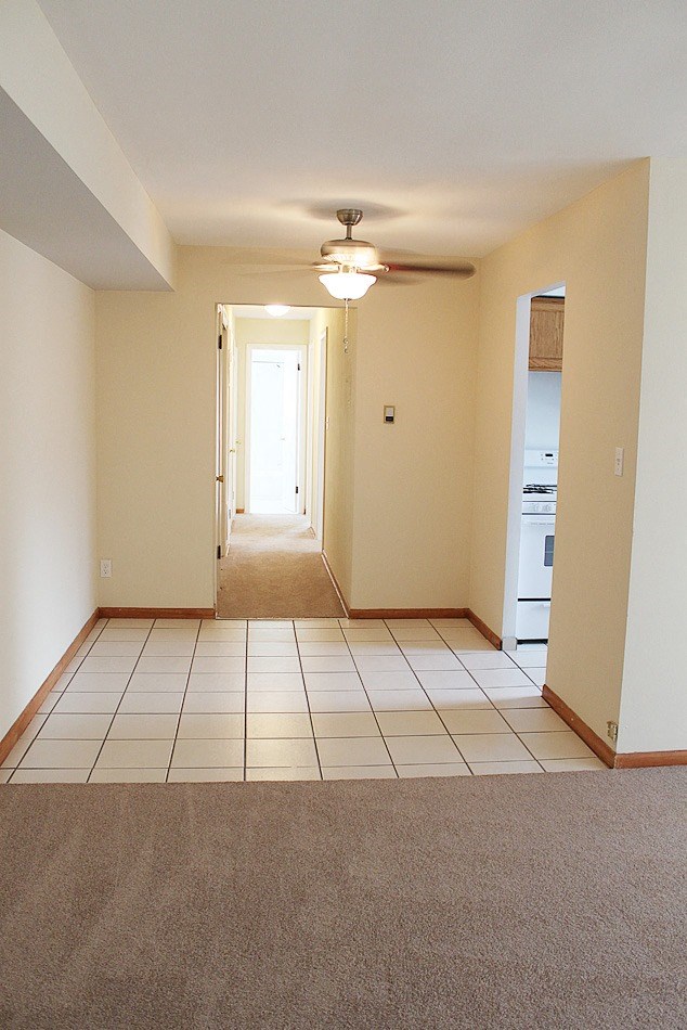 an empty living room with tile floors and a ceiling fan