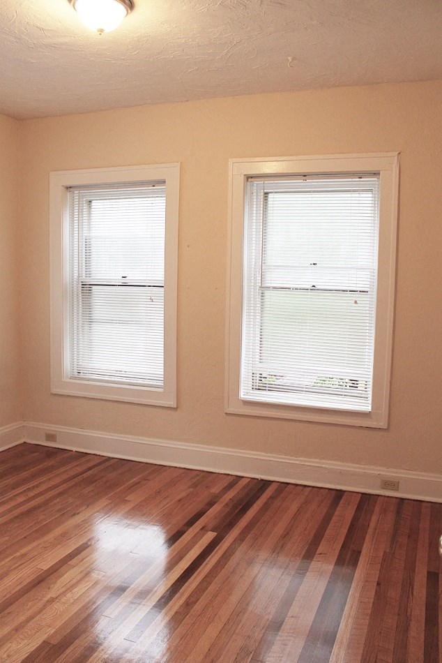 a living room with two windows and a hard wood floor