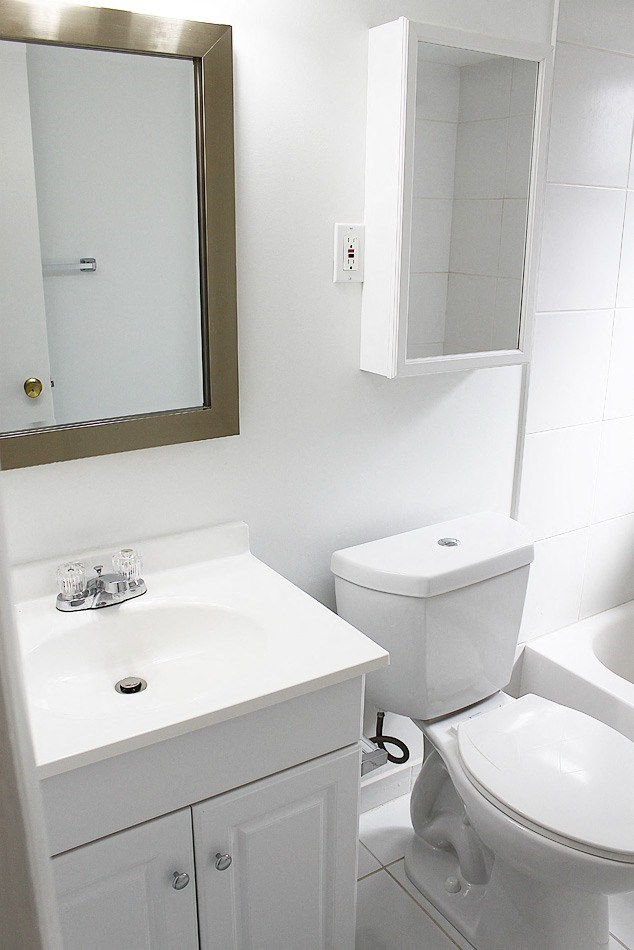 a white bathroom with a sink toilet and a mirror