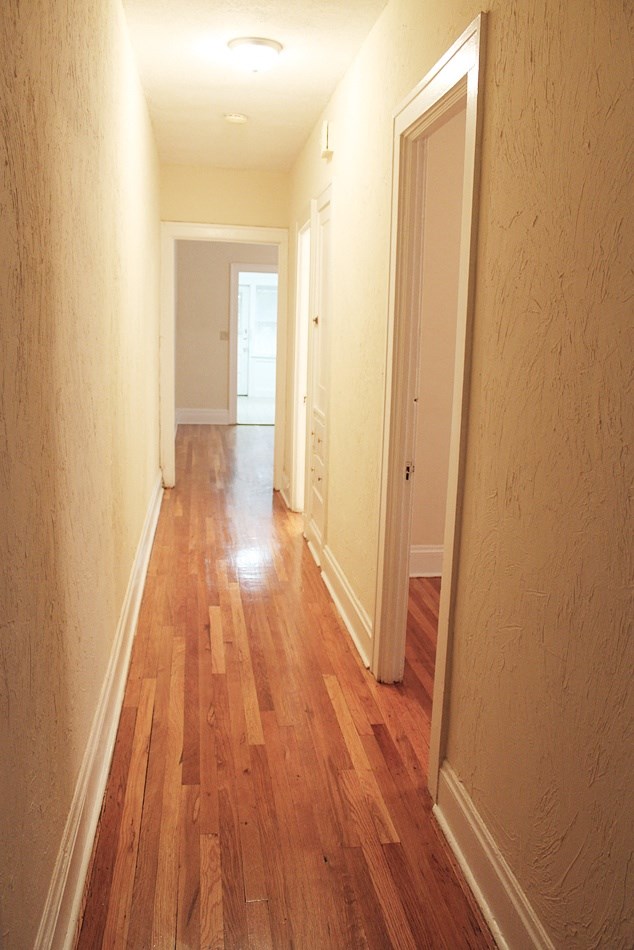 a hallway with wood flooring and a door to a bedroom