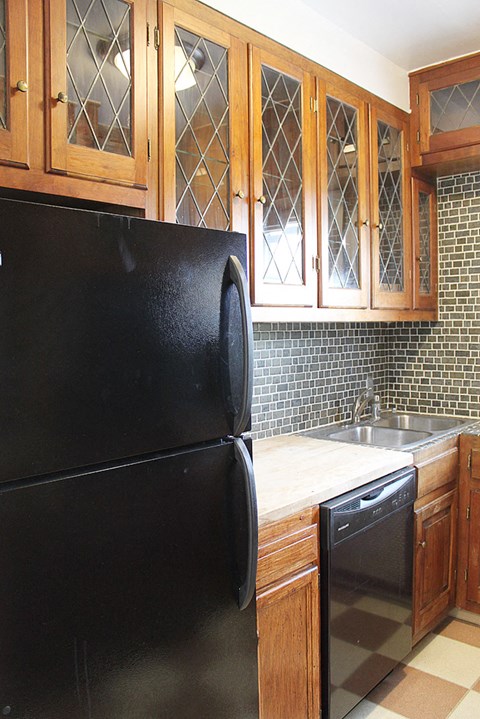 a kitchen with a black refrigerator and wooden cabinets