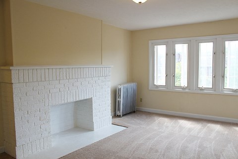 A white fireplace in a room with a carpet.