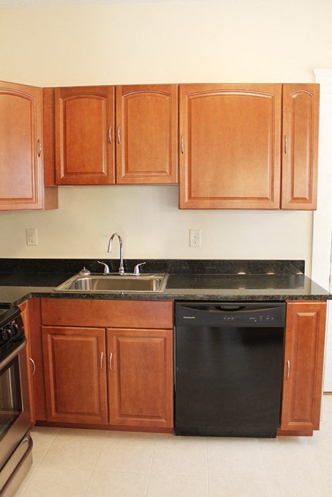 A kitchen with wooden cabinets and black countertops.