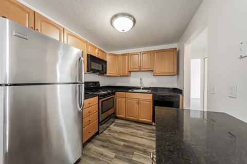 A kitchen with a stainless steel refrigerator and wooden cabinets.