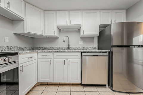 A kitchen with white cabinets and a stainless steel refrigerator.