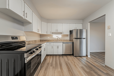 A kitchen with a black stove top oven and white cabinets.