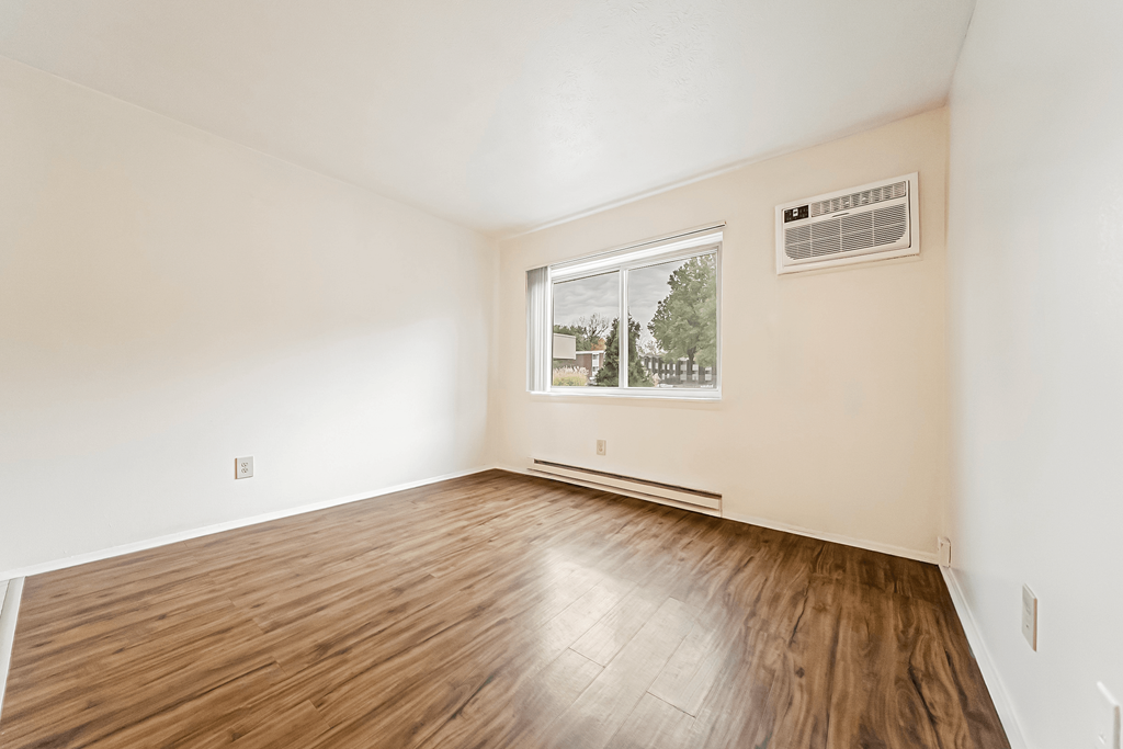 A room with a window and a wooden floor.