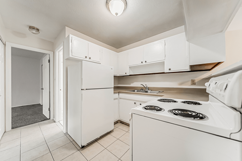 A white kitchen with a stove and a refrigerator.