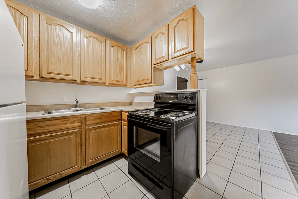 A kitchen with wooden cabinets and a black oven.
