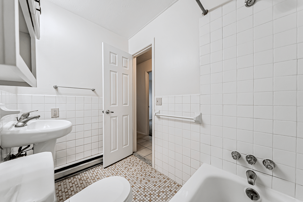 A white bathroom with a toilet, sink, and bathtub.