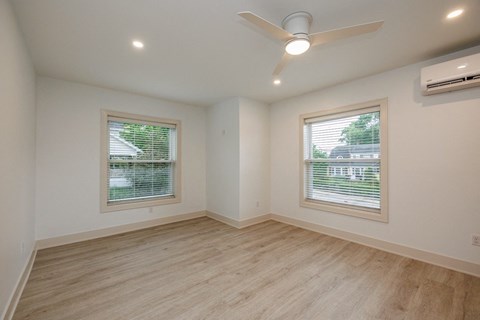 an empty living room with a ceiling fan and two windows