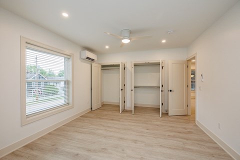 a bedroom with a closet and a window and a ceiling fan