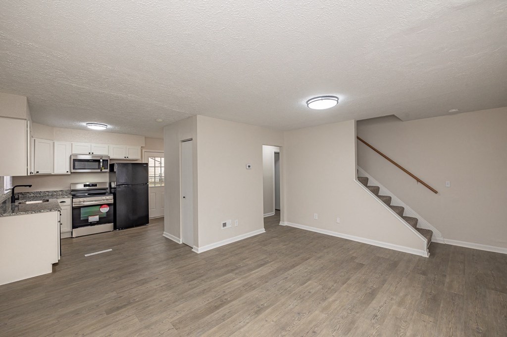 A spacious living room off of the kitchen with a staircase leading to the upper floor.