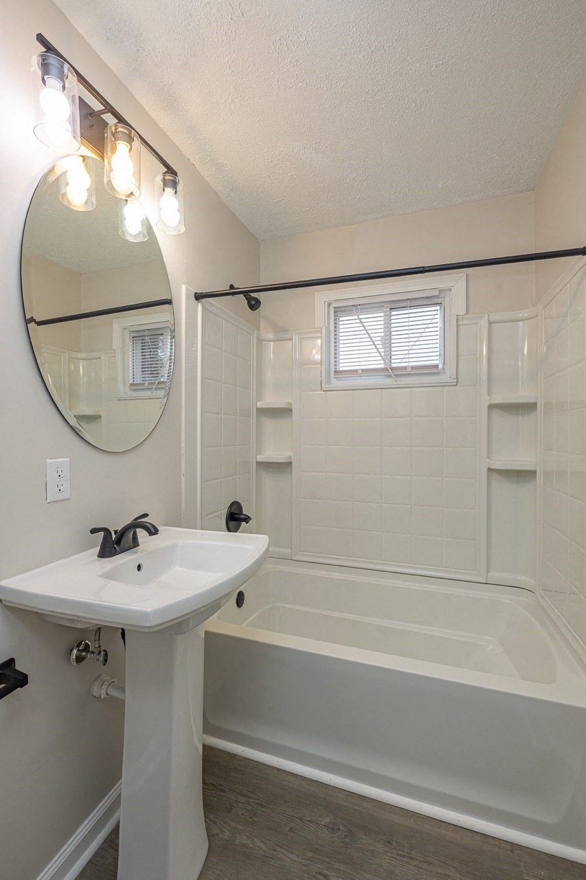 Renovated bathroom with standing sink and white tub.