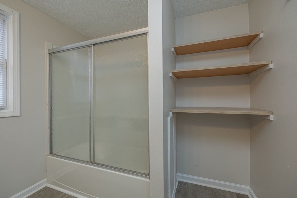 Bathroom featuring built-in linen shelving and storage space.