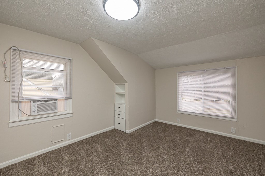 Updated bedroom with new carpeting, a large window, and built-in drawers.