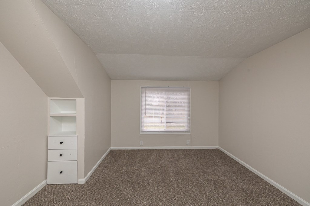 Upstairs bedroom with a window and a white built-in dresser with drawers.