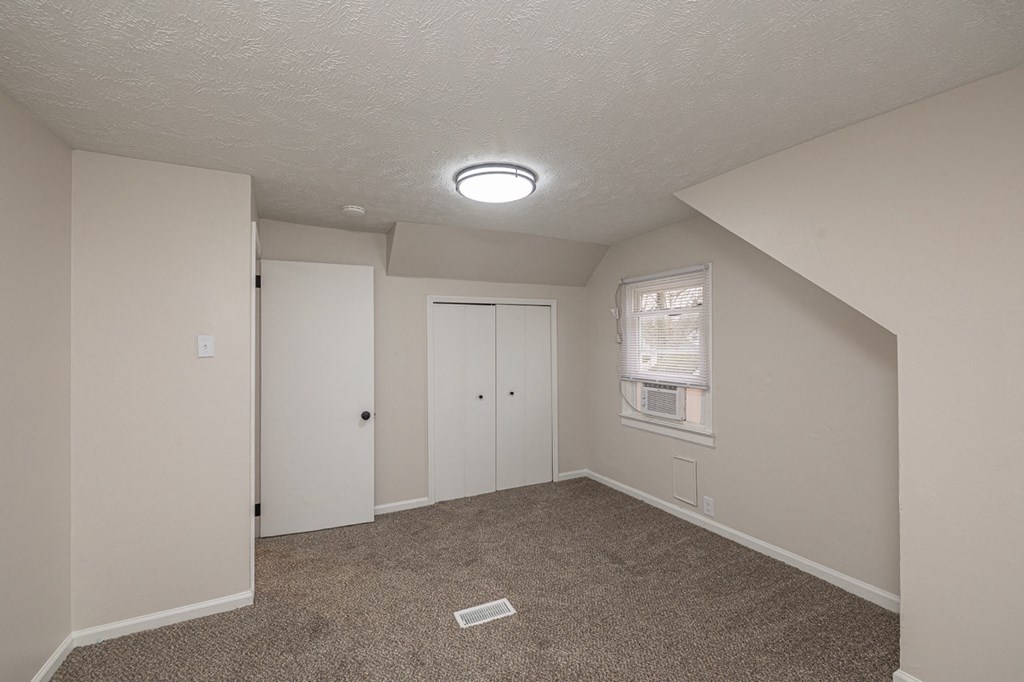 Upstairs bedroom with a carpeted floor, double closet, and window.