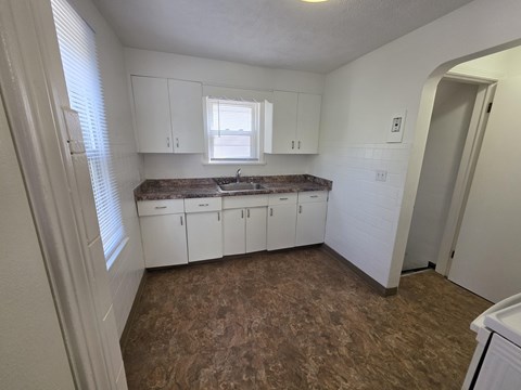 A kitchen with white cabinets and a brown floor.