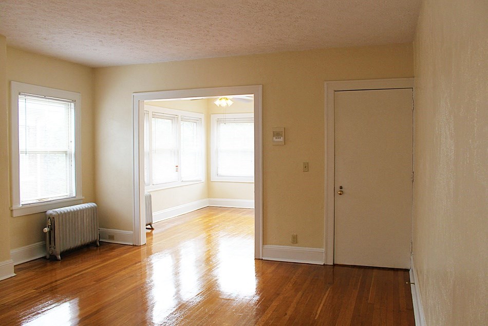 an empty living room with wood floors and a door