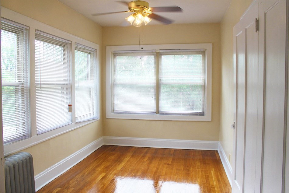 an empty room with a ceiling fan and three windows