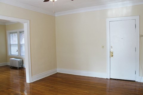an empty living room with a white door and wood floors
