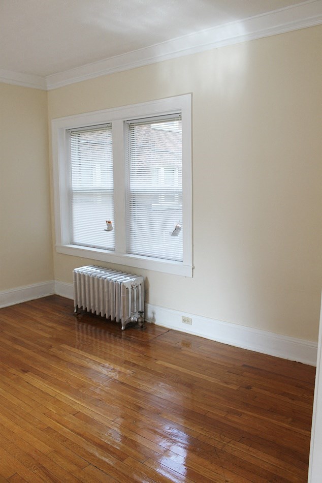 a room with a wood floor and a radiator and a window