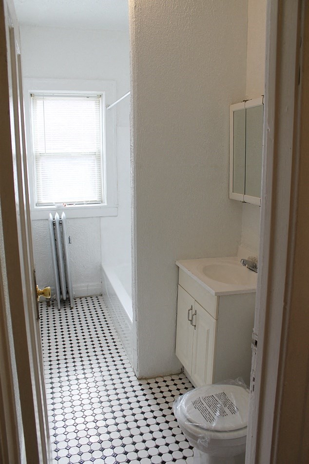 the bathroom has a checkered floor and a toilet and a sink