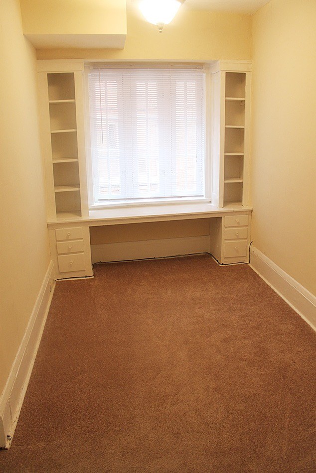 a room with a window and white shelves and a carpet