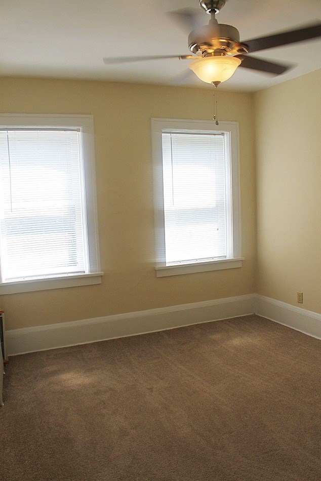 a living room with two windows and a ceiling fan
