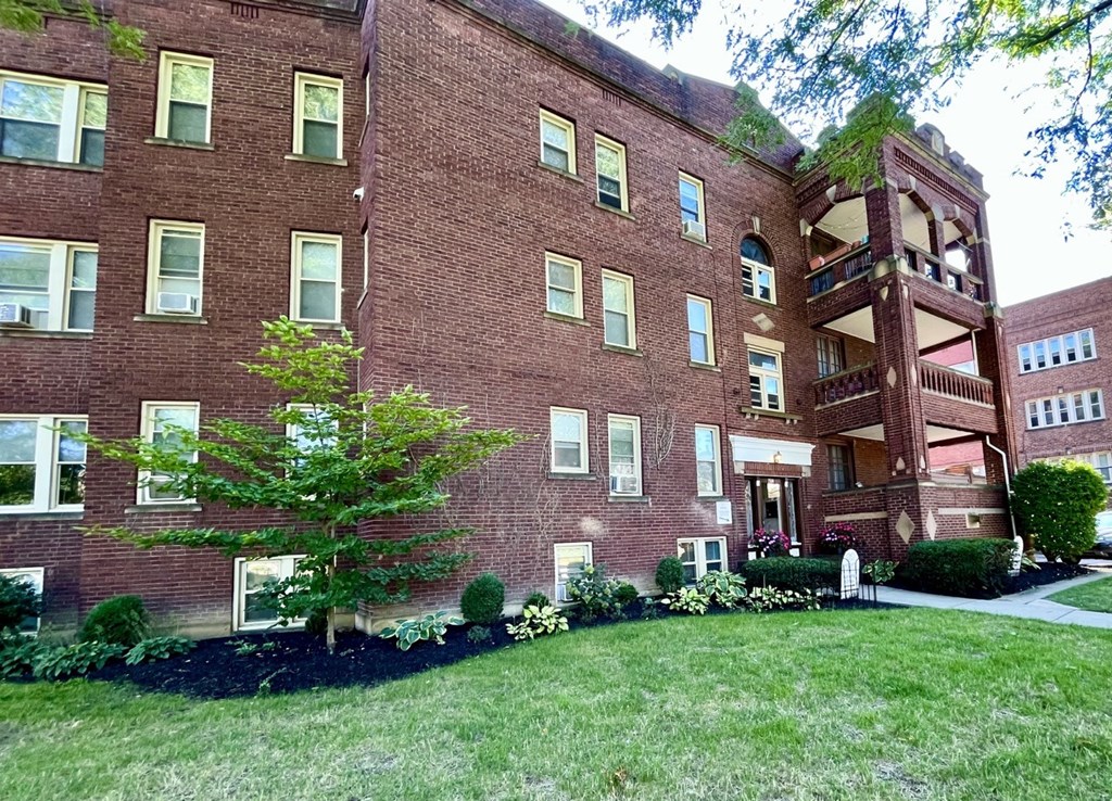 A red brick building with a tree in front.