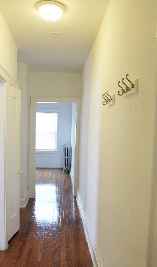 a hallway with white walls and wooden floors and a window