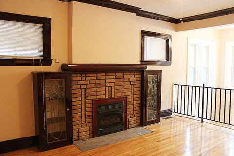 a living room with a brick fireplace and a wooden floor