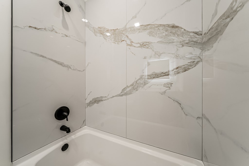 A white bathroom with a marble patterned shower.