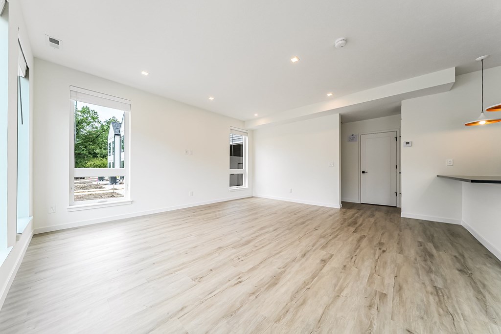 A spacious room with wooden flooring and white walls.
