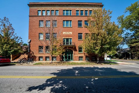 A red brick building with a green door and windows.