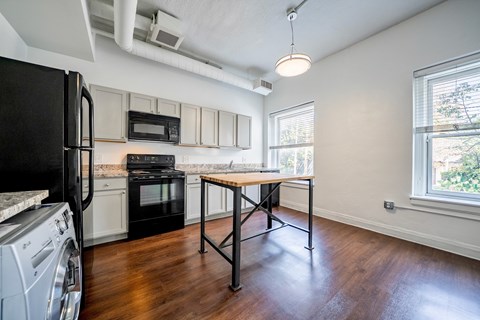 A black fridge is on the left of a kitchen with a black oven and a black microwave.