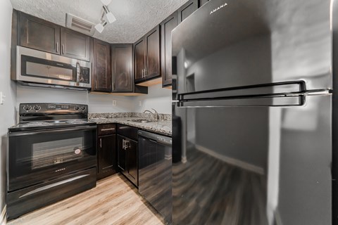 A kitchen with black cabinets and a stainless steel refrigerator.