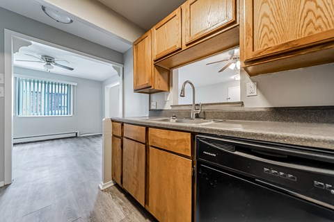 A kitchen with wooden cabinets and a black dishwasher at Integrity Chardon Apartments, Chardon,  Ohio