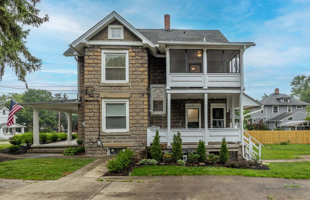 a stone house with a porch and a flag in front of it