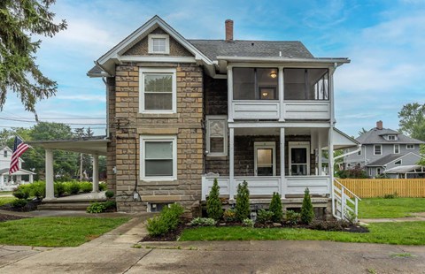 a stone house with a porch and a flag in front of it