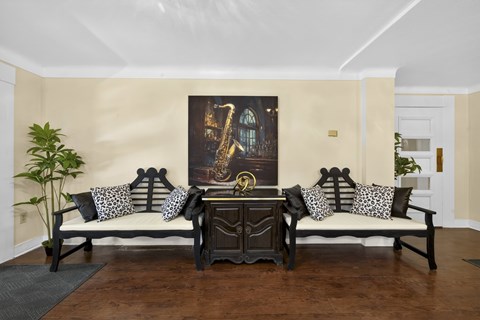 A living room with a sofa set and a painting on the wall.