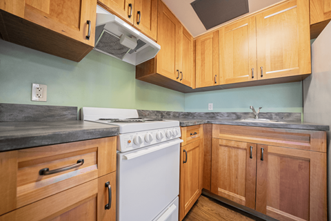 A kitchen with a white stove and wooden cabinets.