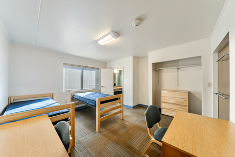 A bedroom with two beds and a chair.
