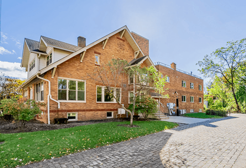 A large brick house with a cobblestone driveway in front.