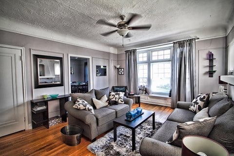a living room with a gray couch and a ceiling fan
