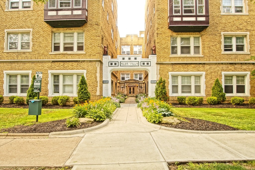 the front entrance of a building with a sidewalk and grass