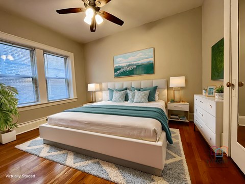 A bedroom with a bed, nightstand, and a ceiling fan.